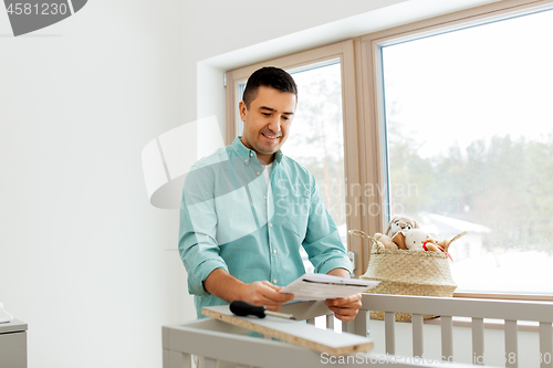 Image of father with manual assembling baby bed at home