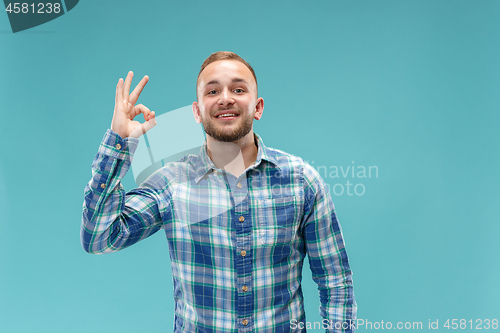 Image of The happy businessman standing and smiling against blue background.