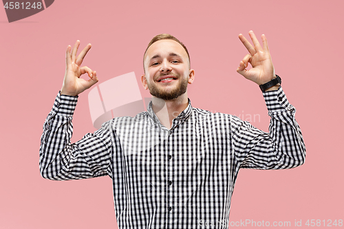 Image of The happy businessman standing and smiling against pink background.