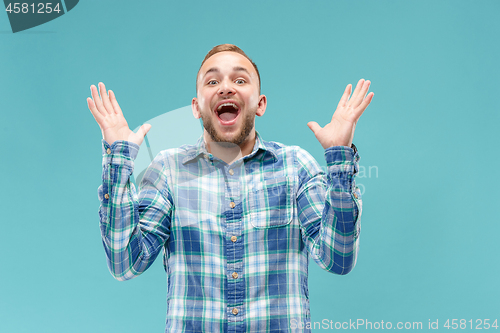 Image of The young attractive man looking suprised isolated on blue
