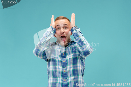 Image of The young attractive man looking suprised isolated on blue