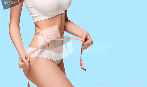 Image of The girl taking measurements of her body, blue background.