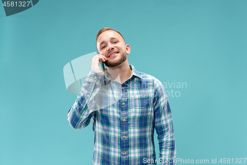 Image of Young handsome man talking over phone and looking away.