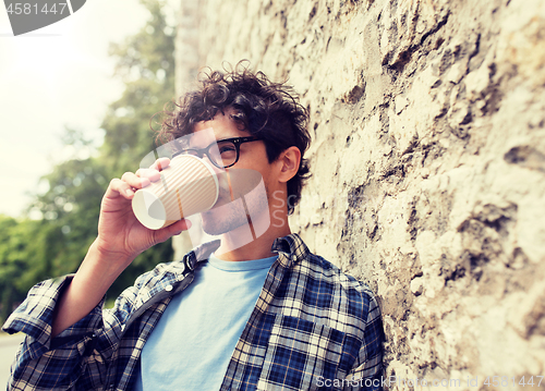 Image of man in eyeglasses drinking coffee over street wall