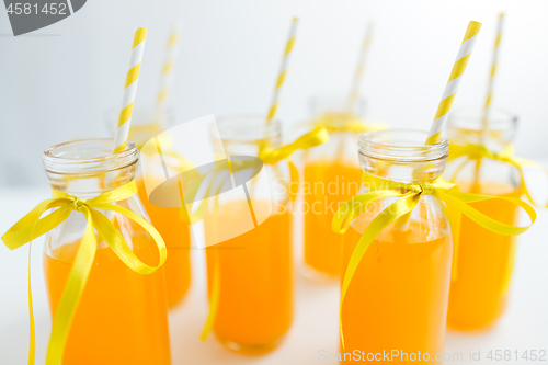 Image of orange juice in glass bottles with paper straws