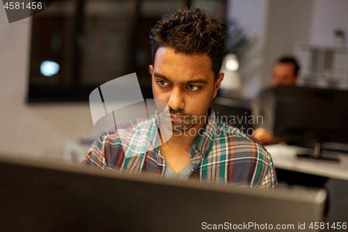 Image of creative man with computer working at night office