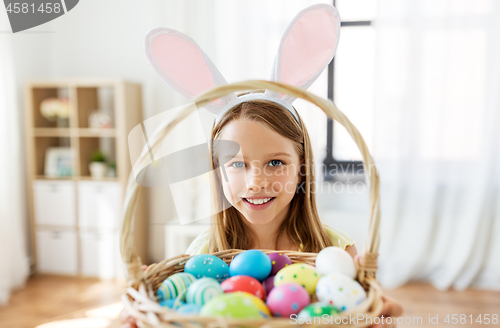 Image of happy girl with colored easter eggs at home