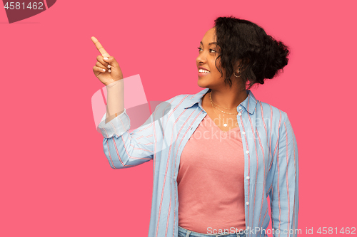 Image of happy african american woman pointing finger up