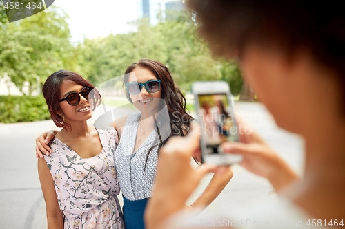 Image of woman photographing her friends in summer park