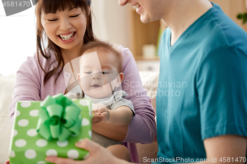 Image of happy family with baby son and gift at home