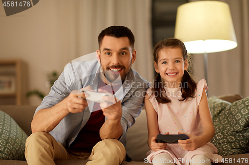 Image of father and daughter playing video game at home