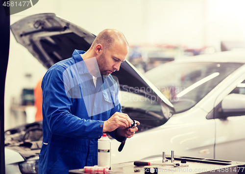 Image of mechanic man with wrench repairing car at workshop