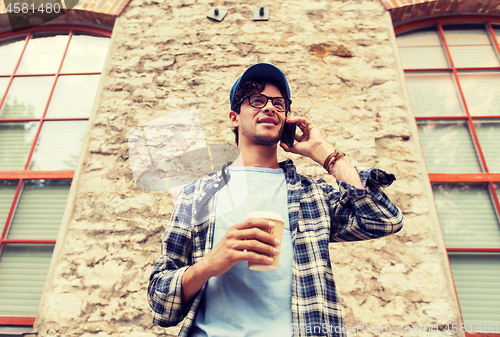 Image of man with smartphone drinking coffee on city street