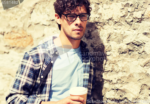 Image of man in eyeglasses drinking coffee over street wall