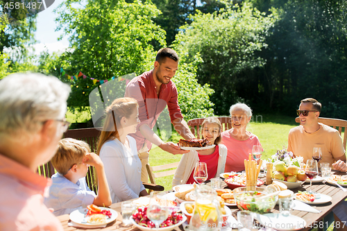 Image of family having dinner or barbecue at summer garden