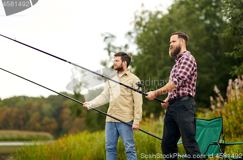 Image of friends with fishing rods at lake or river