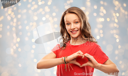 Image of smiling teenage girl in red making hand heart