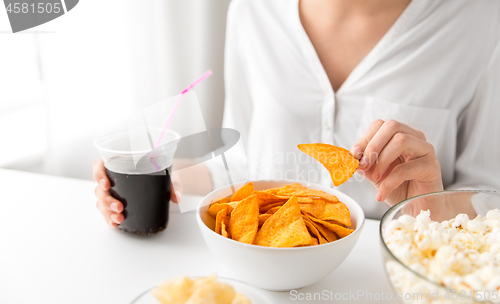 Image of close up of woman eating corn nachos with cola