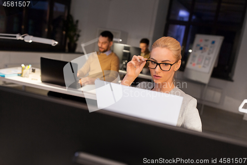 Image of businesswoman with papers working at night office