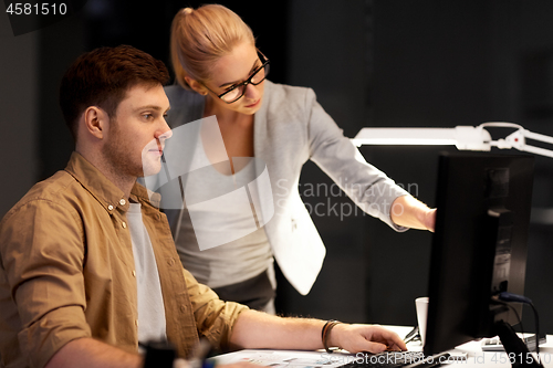 Image of business team with computer working late at office