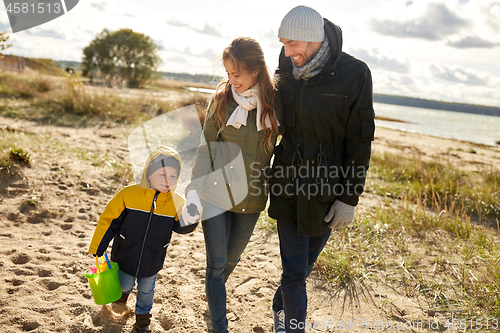 Image of happy family walking along autumn beach