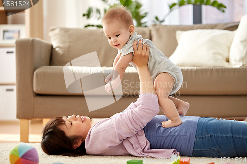 Image of happy mother playing with little baby son at home