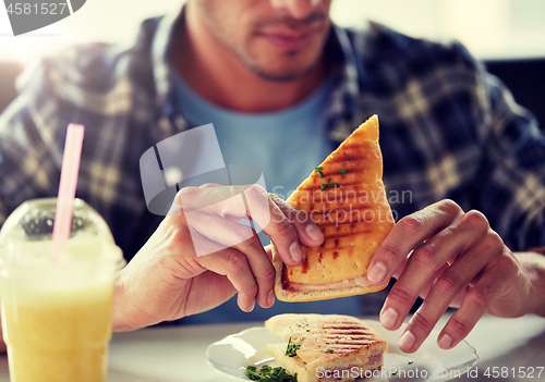 Image of close up of man eating sandwich at cafe for lunch