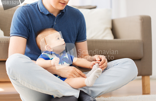 Image of father with baby son sitting on floor at home