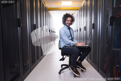 Image of engineer working on a laptop in server room