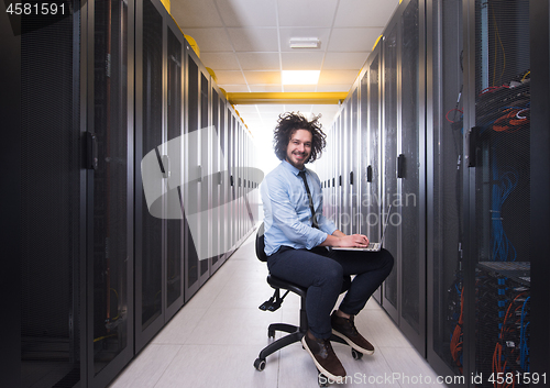 Image of engineer working on a laptop in server room