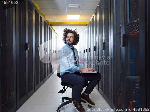 Image of engineer working on a laptop in server room