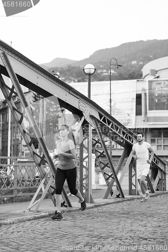 Image of woman jogging across the bridge at sunny morning