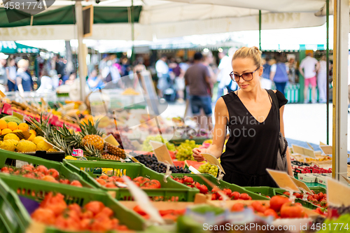 Image of Woman buying fruits and vegetables at local food market. Market stall with variety of organic vegetable