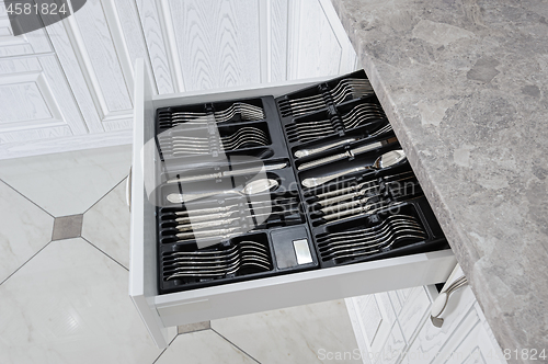 Image of drawer with silver cutlery in modern white kitchen