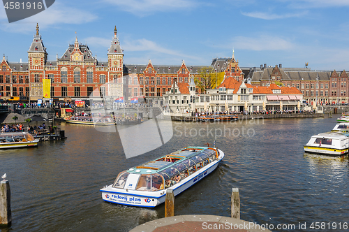 Image of Tourists sightseeng at Canal Boats next tot Central Station of Amsterdam