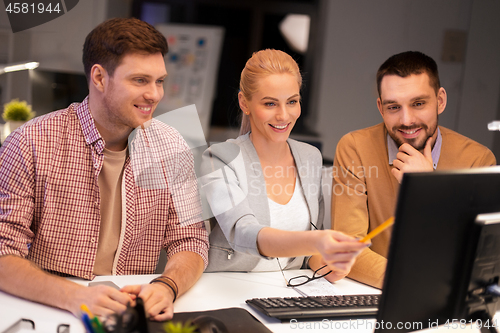 Image of business team with computer working late at office