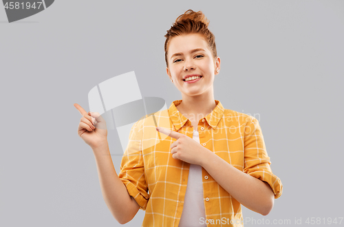 Image of red haired teenage girl pointing fingers left