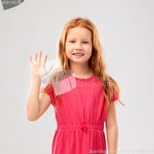 Image of smiling red haired girl in pink dress waving hand