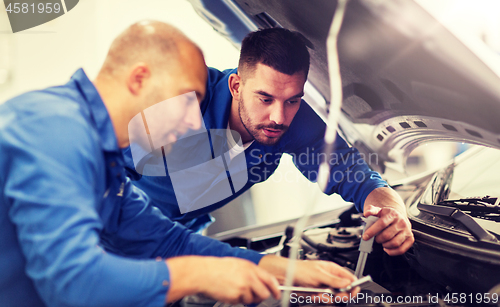 Image of mechanic men with wrench repairing car at workshop