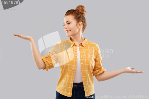 Image of happy red haired teenage girl holding empty hands