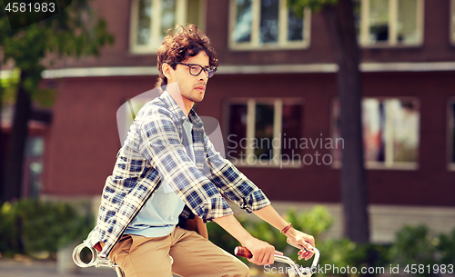 Image of young hipster man with bag riding fixed gear bike