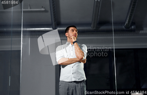 Image of businessman looking at glass wall at night office