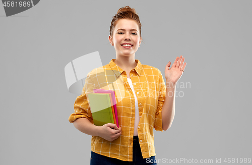 Image of teenage student girl with books waving hand