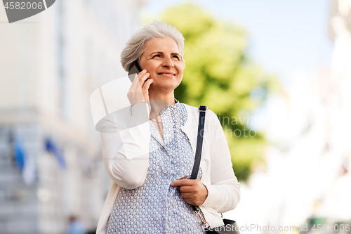 Image of senior woman calling on smartphone in city