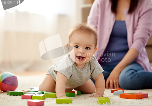 Image of happy baby boy with toy blocks on carpet at home