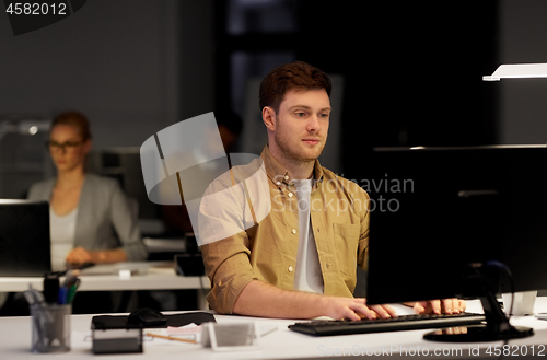 Image of man with computer working late at night office