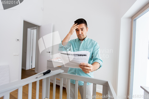 Image of father with manual assembling baby bed at home