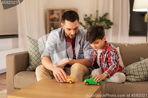 Image of father and son playing with toy cars at home