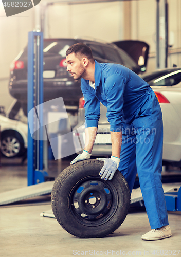 Image of mechanic with wheel tire at car workshop