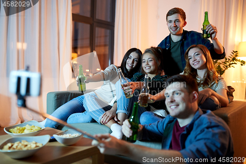 Image of friends taking picture by selfie stick at home